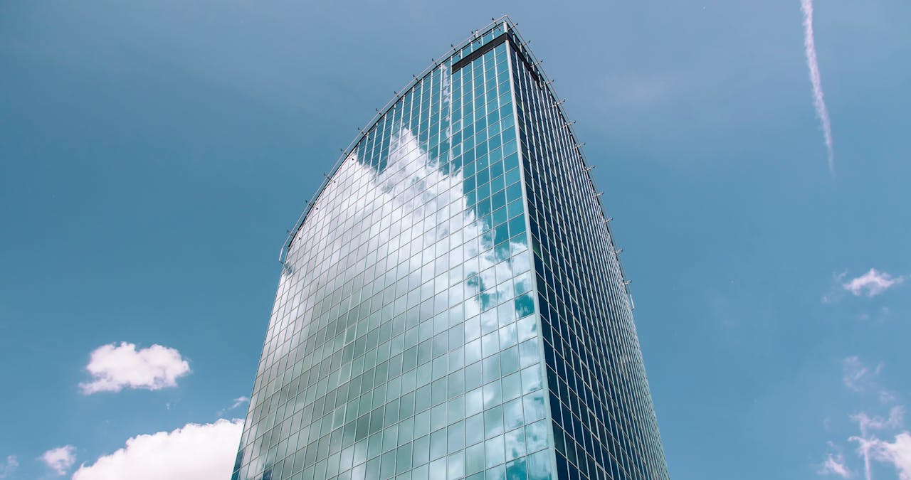A sleek, modern skyscraper in Warsaw, Poland with a reflective glass facade against a blue sky.